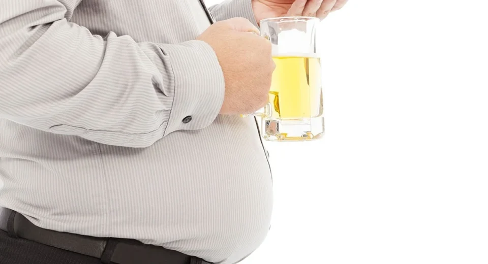 A picture of a man holding and drinking a glass of alcohol